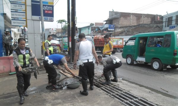 Personil satlantas Polres Bandung bersihkan saluran air di Jalan Raya Cinunuk, Cileunyi, Jumat (3/3). by iwa/bbcom